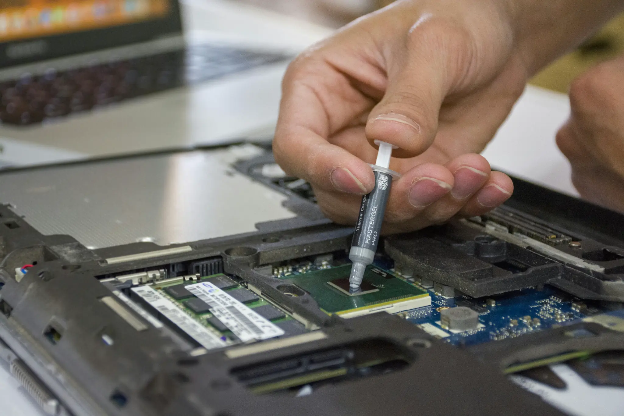 Laptop repair technician applying thermal paste to CPU